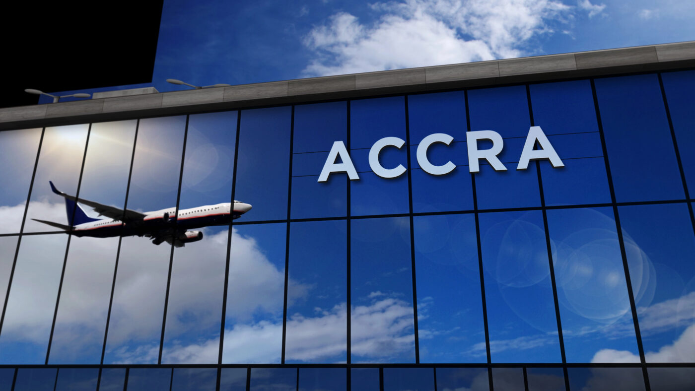 Plane approaching Accra reflected on airport glass building